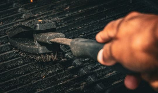 Man scrubbing a rusty grill